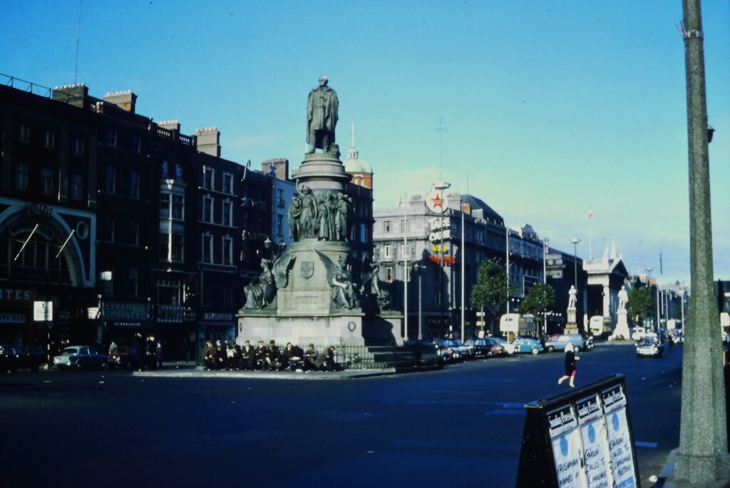 A statue of a man on top of a large pedestal. A group of young men sit at the base
