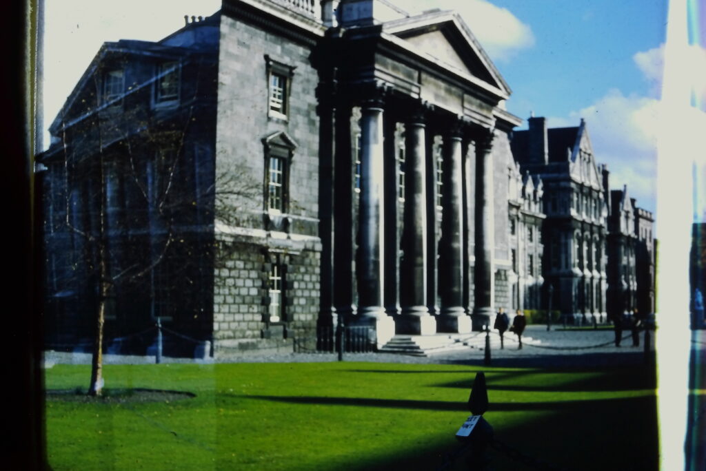 A stone building with huge columns out front and a lush grassy field