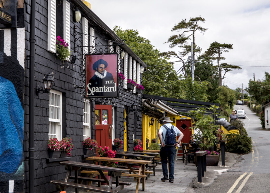 A building with dark shingles. The sign reads "The Spaniard" and features a man dressed in what one presumes is centuries old Spanish fashion