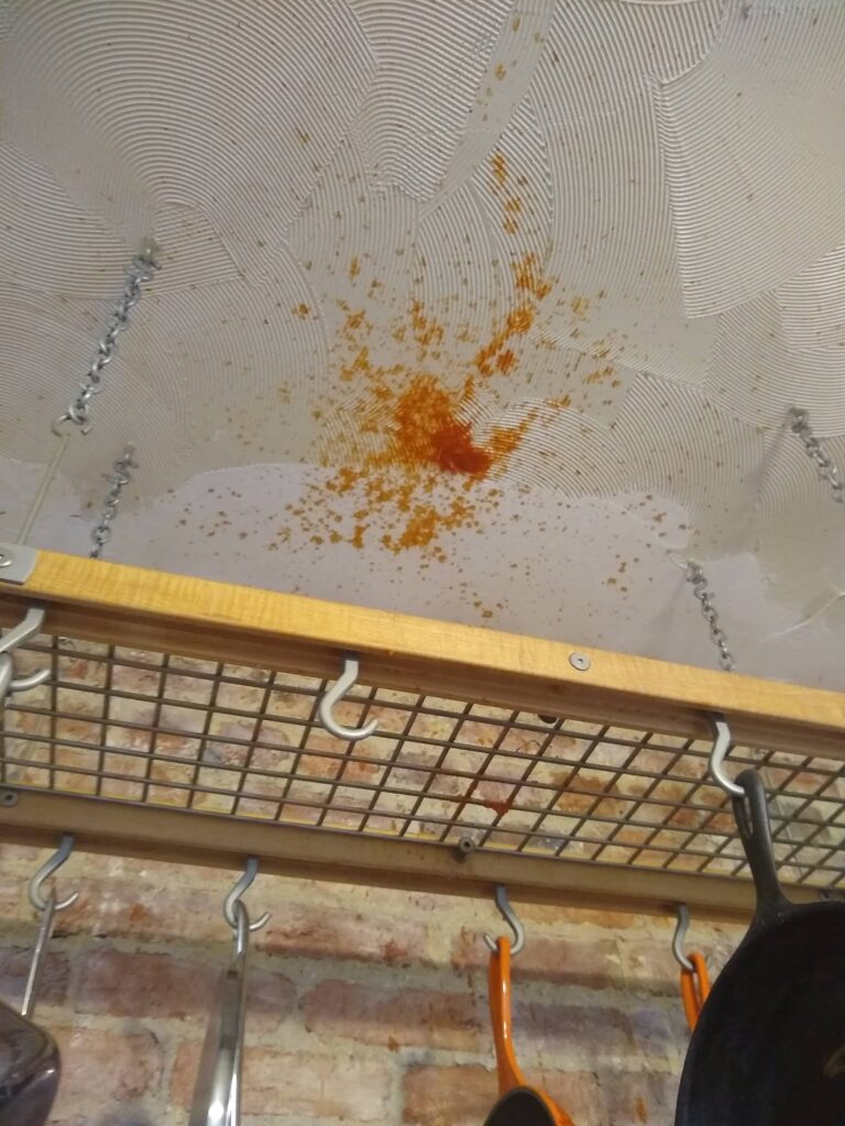 A splatter of Sriracha on the ceiling, shown through the pot rack